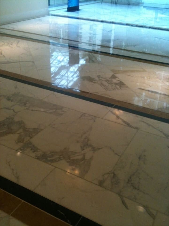 Mirror-polished white marble lobby floor with bold grey veining and dark accent borders