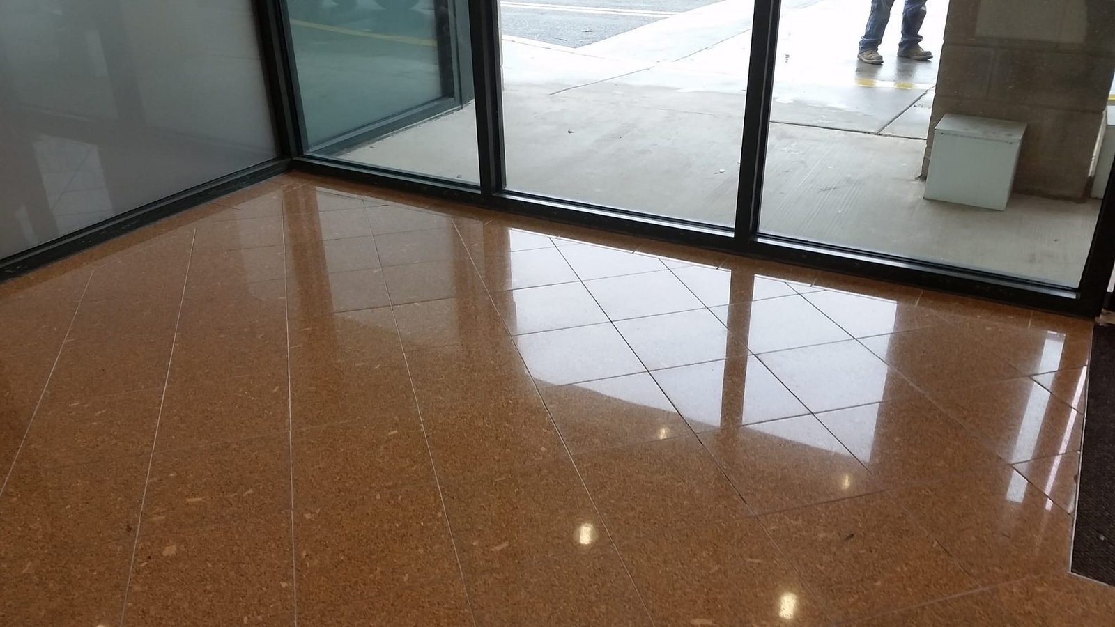 Polished amber granite tile floor in a glass-walled commercial entrance