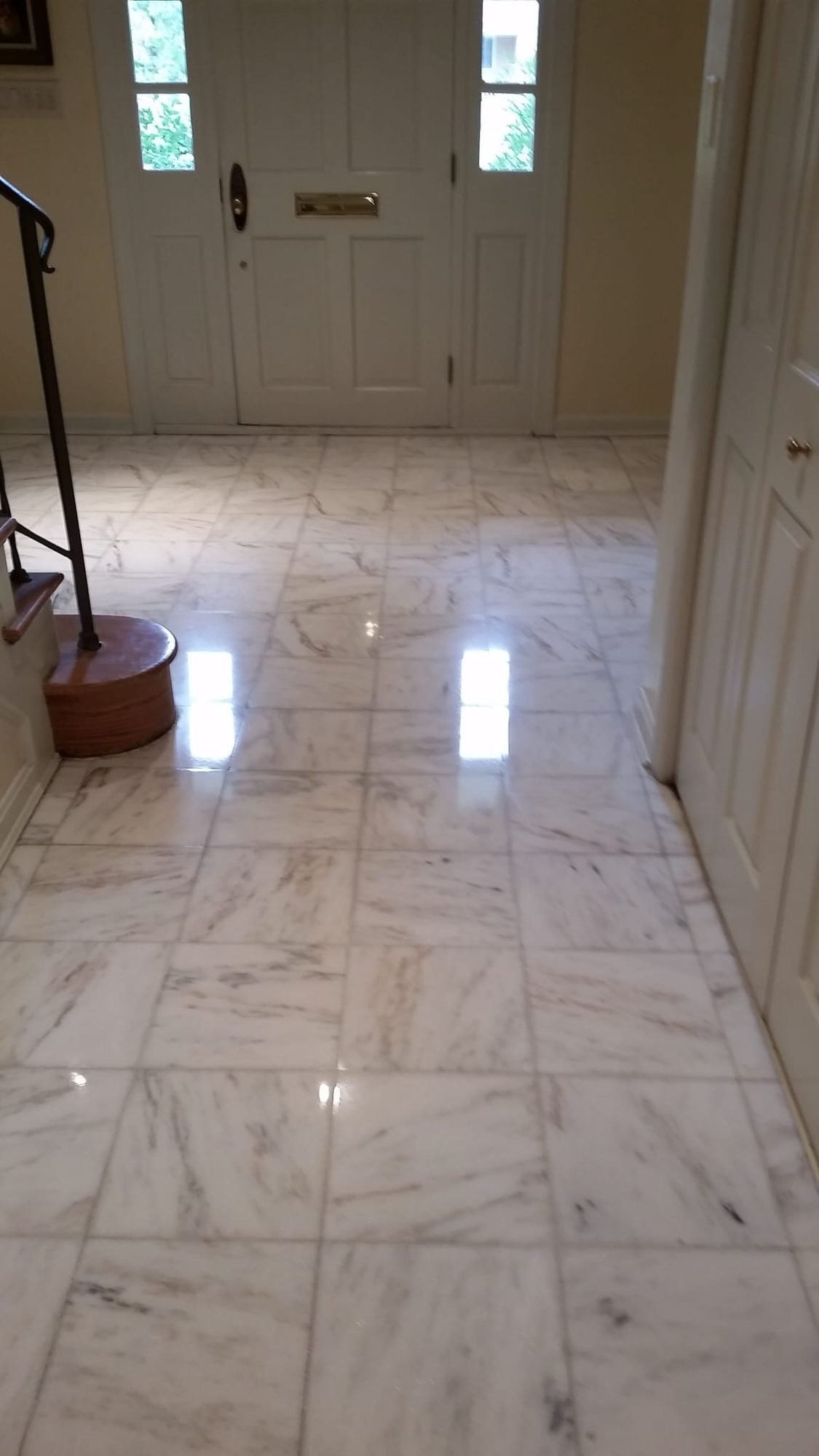 Polished white-and-grey marble tile entryway floor at a home's front door
