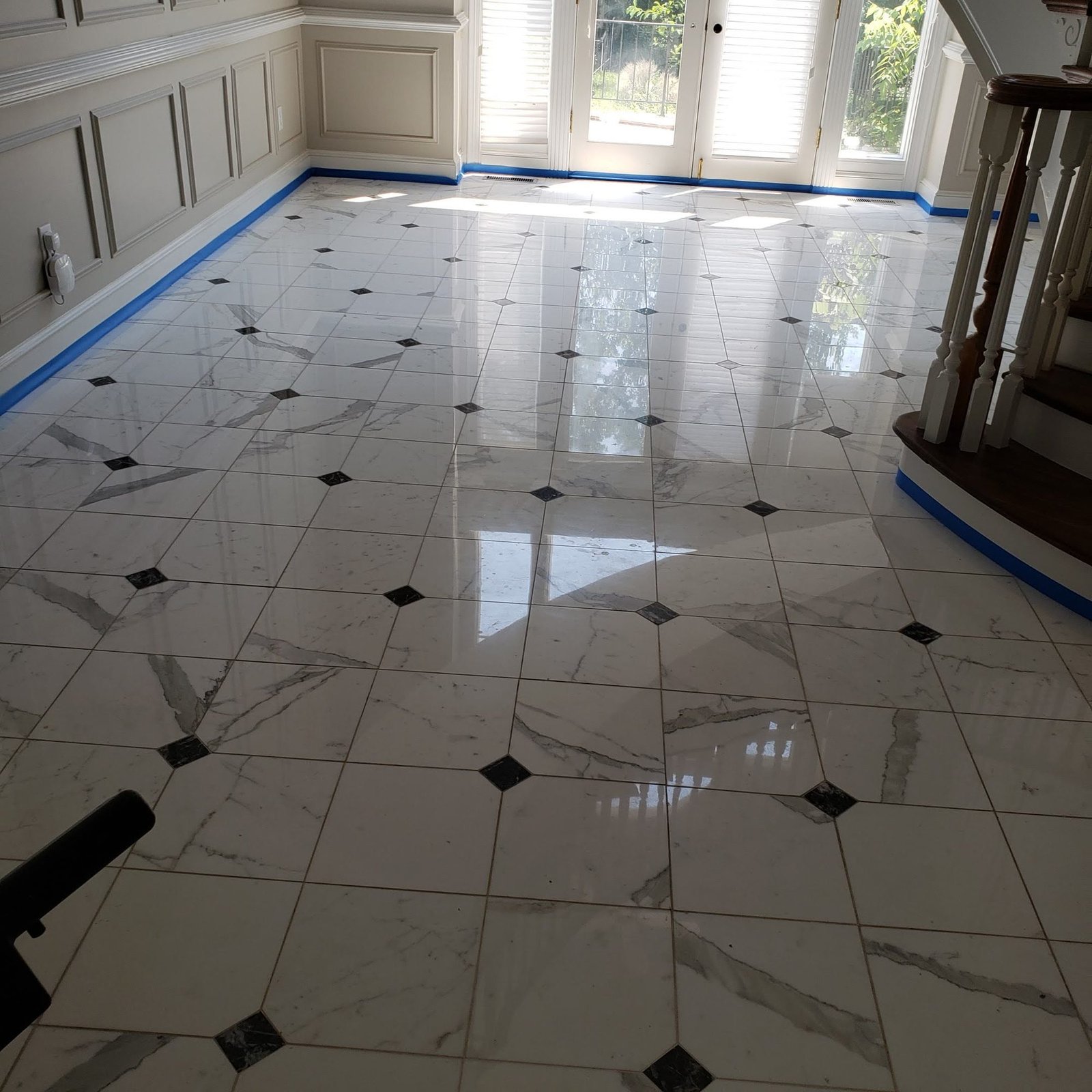 Polished white marble tile with grey veining and black diamond inlays, finished to a high-gloss shine