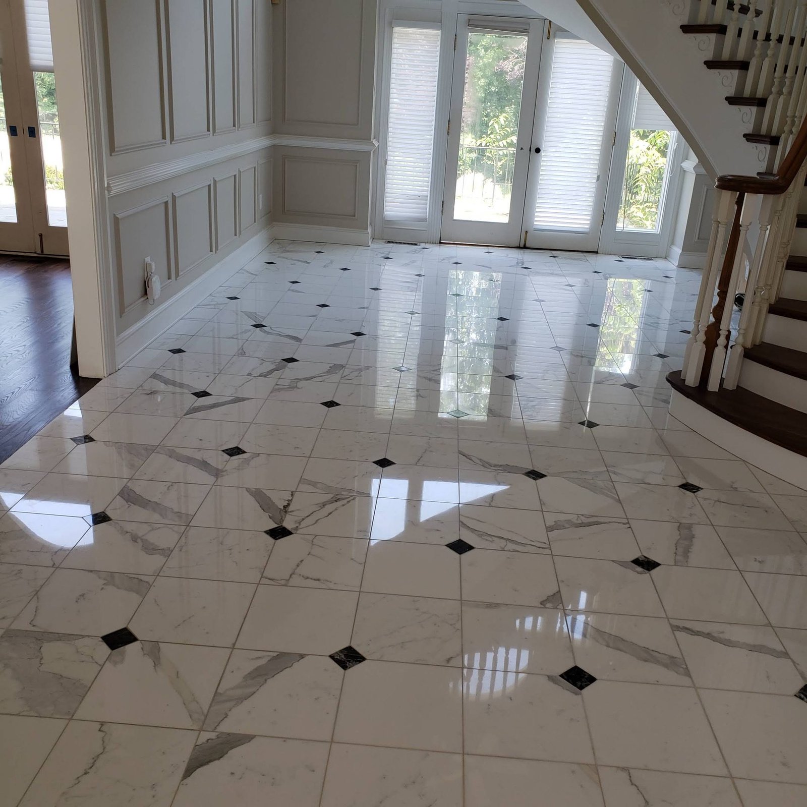 White marble tile installation with diamond inlays polished to a mirror finish beside a staircase