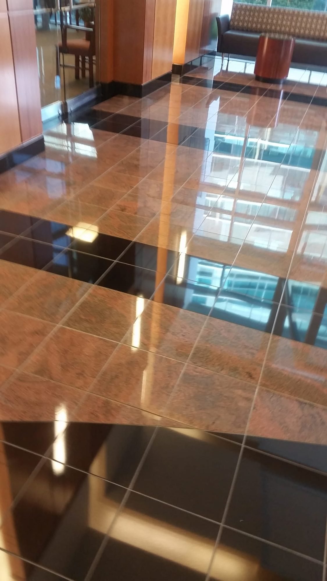 High-gloss brown marble tile floor in a commercial lobby with mirror-like reflections