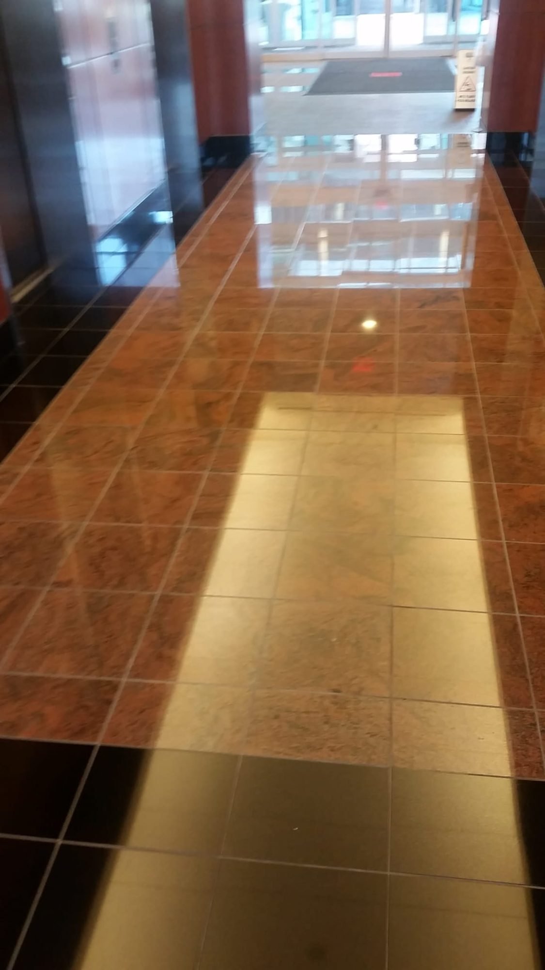 Polished brown marble corridor floor reflecting overhead light in a commercial building