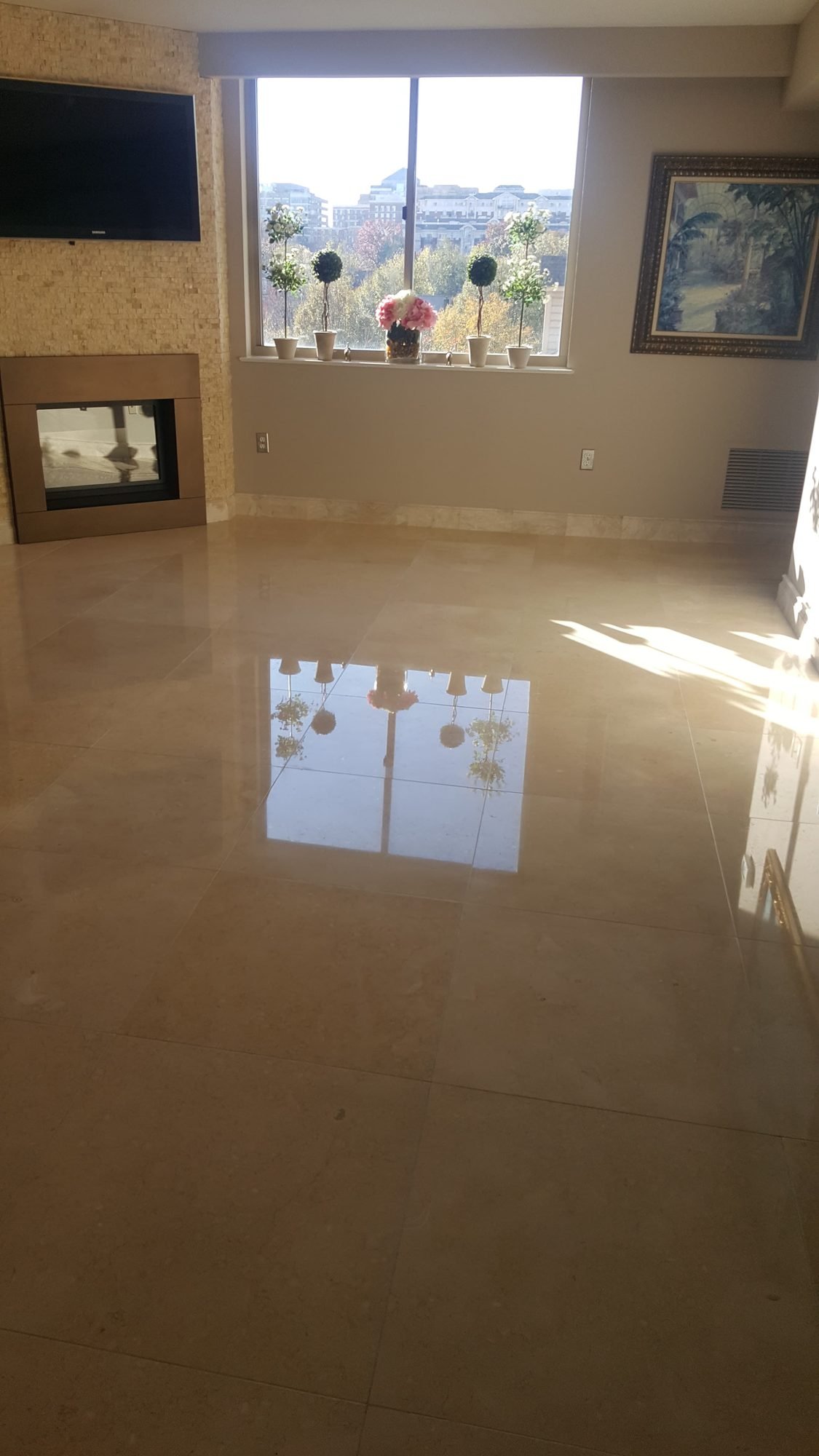 High-gloss polished marble floor reflecting a sunlit window and framed artwork