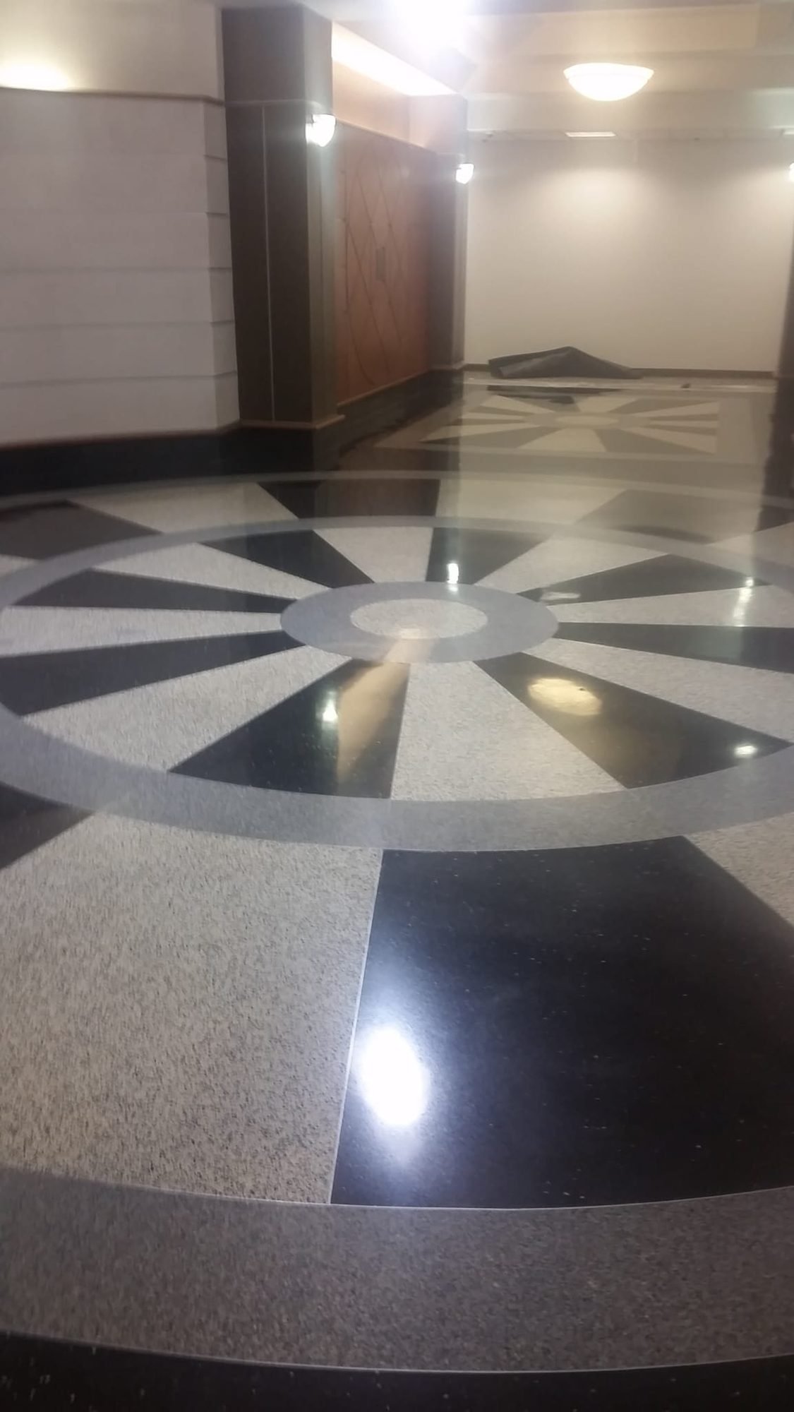 Restored terrazzo floor with a decorative black, grey and white starburst medallion in a lobby