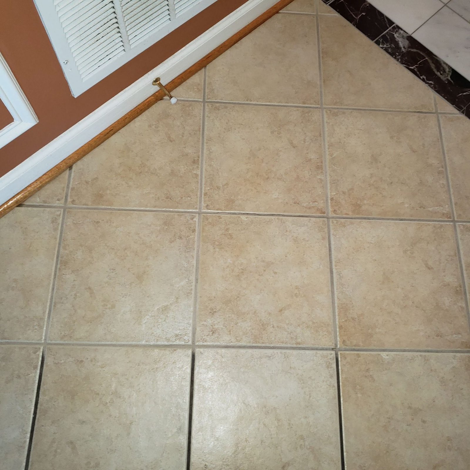 Tan ceramic tile floor with darkened, soiled grout lines before cleaning